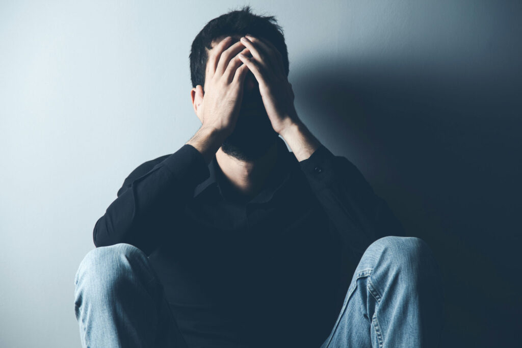 a man sitting down, distressed, considering whether seasonal depression is genetic