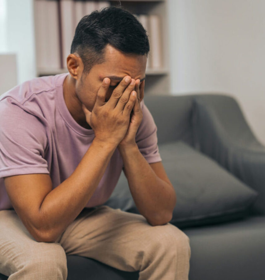 a man sitting on the couch, struggling with schizophrenia